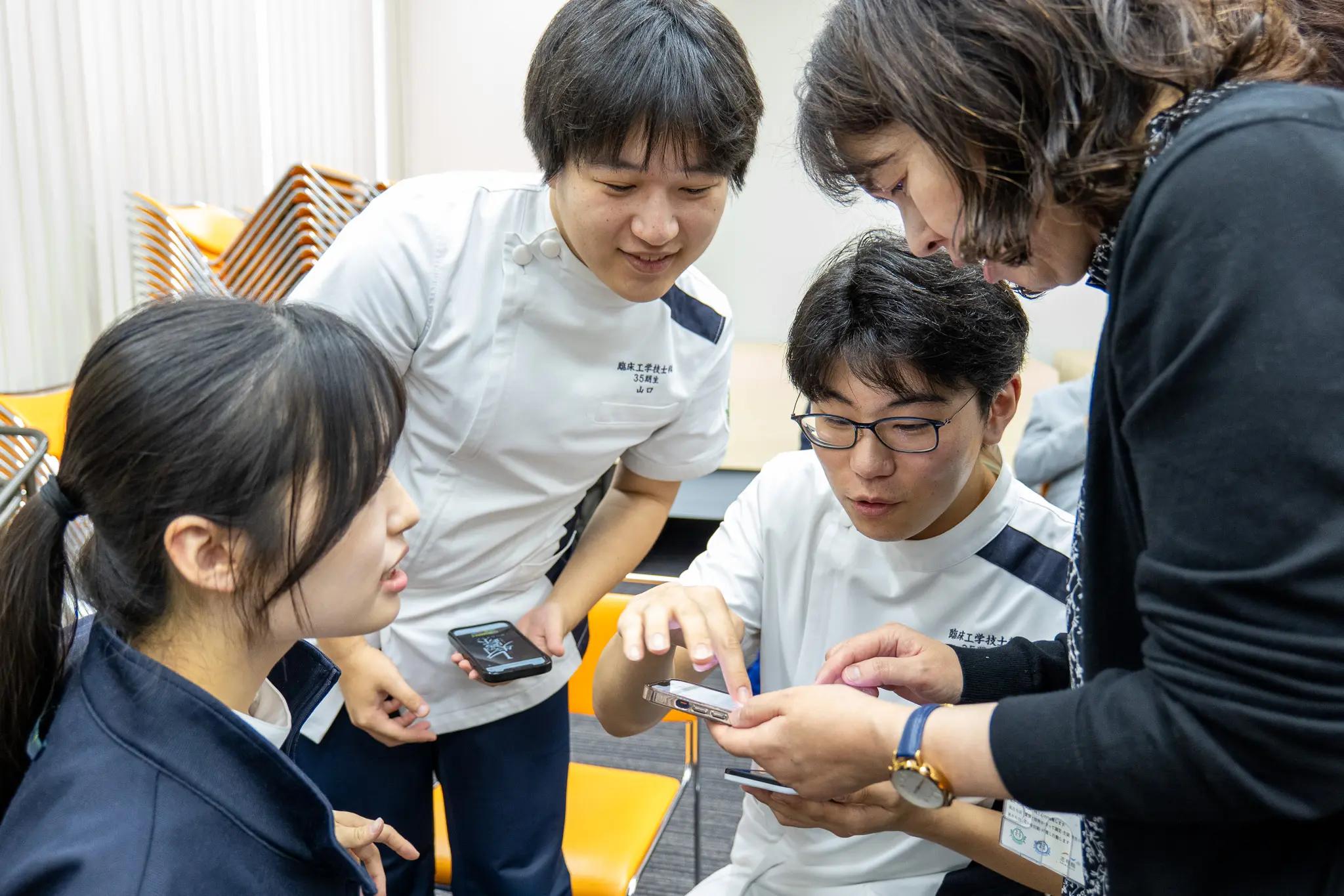 スマホでゲームを体験する高校生・大学生等
