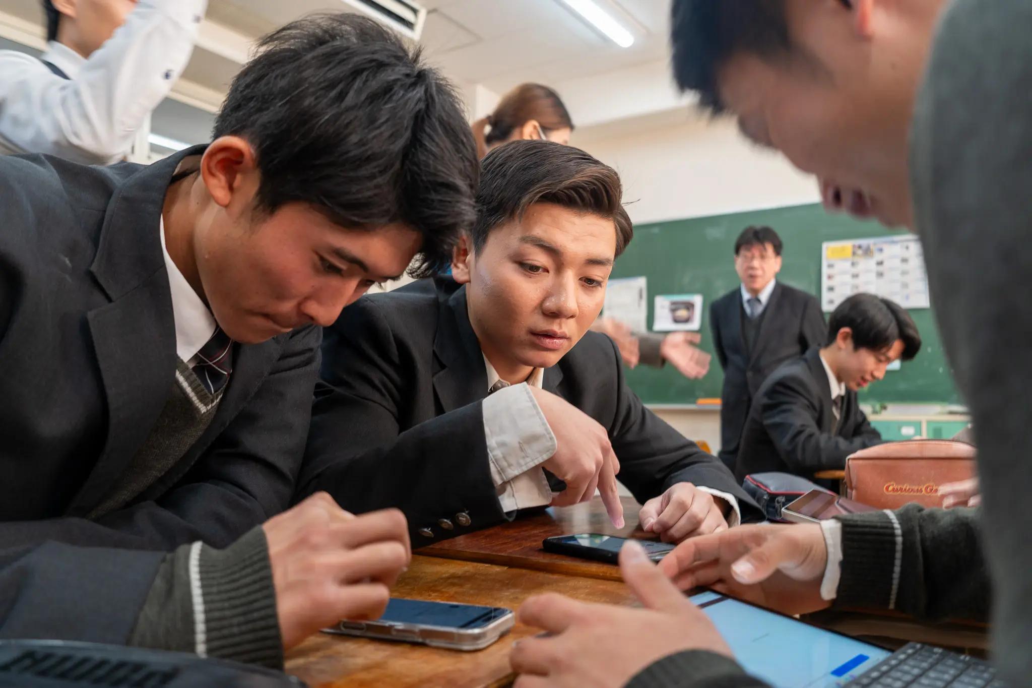 ノートパソコンを見ながら笑顔で取り組む高校生・大学生等